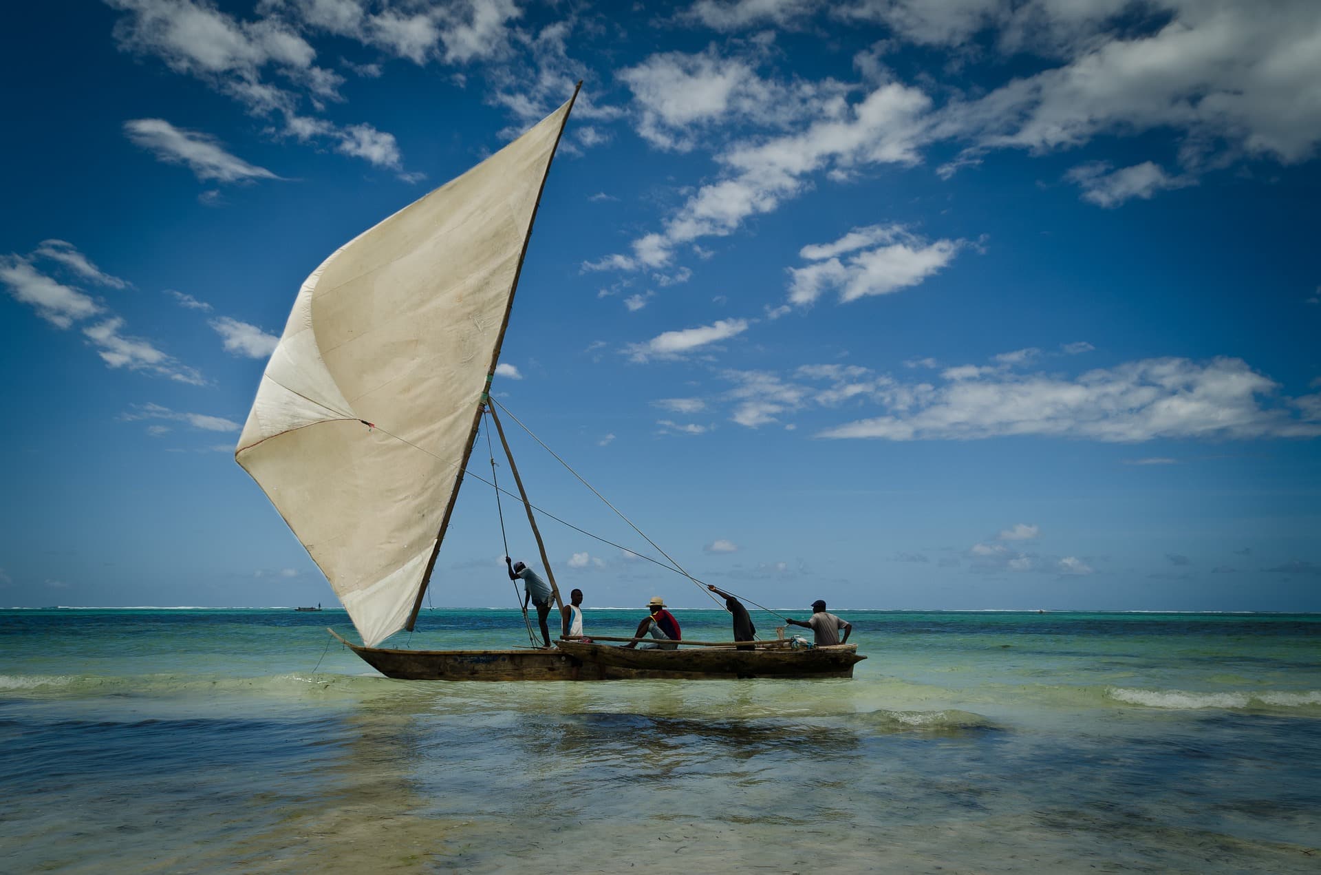 Traditional dhow sailing through shallow turquoise water off Zanzibar